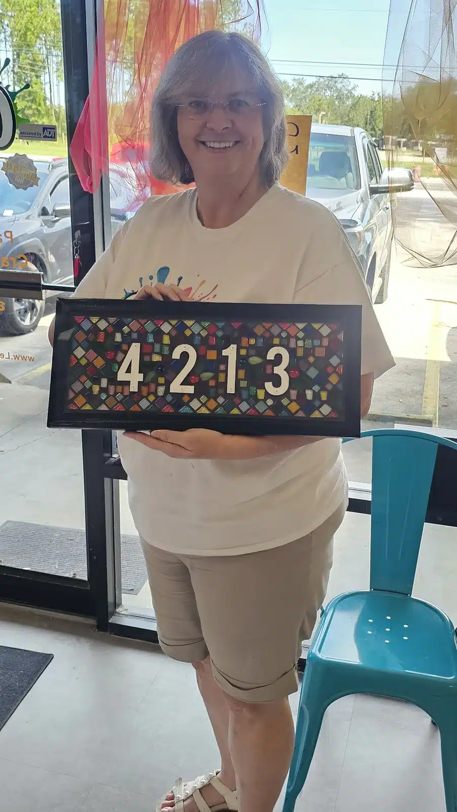 Owner holding a mosaic 4213 address sign at Let's Create Studios, 4213 CR 218, Middleburg, FL