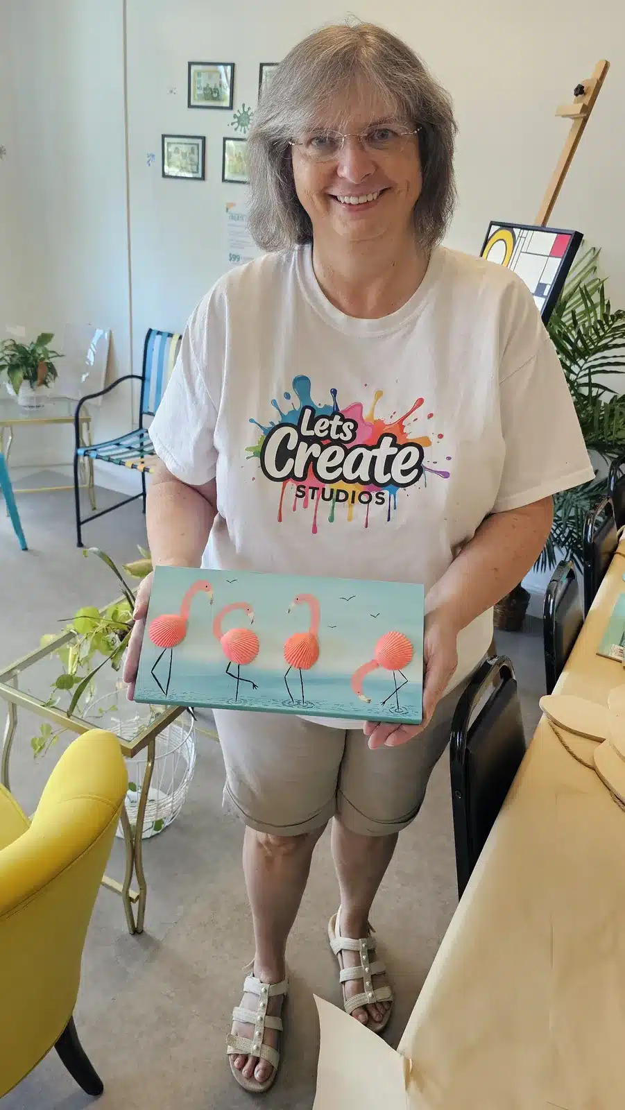 Owner holding a flamingo canvas painting made at Let's Create Studios in Middleburg