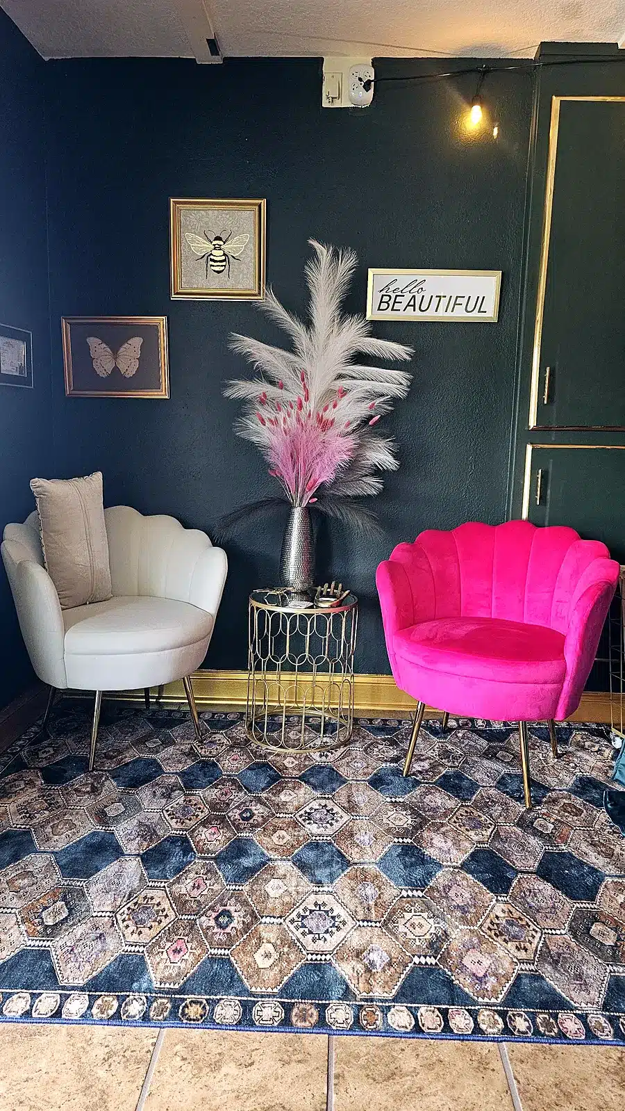 Waiting area at Massage Craving with a pink velvet chair, cream chair and gold accents