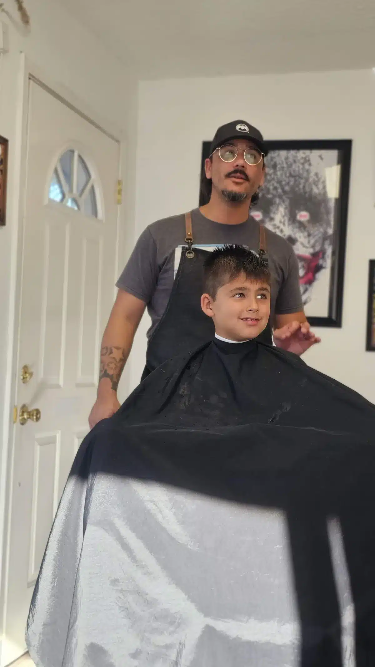 Jay talks with a smiling young client during a haircut at Intermissions Barbershop